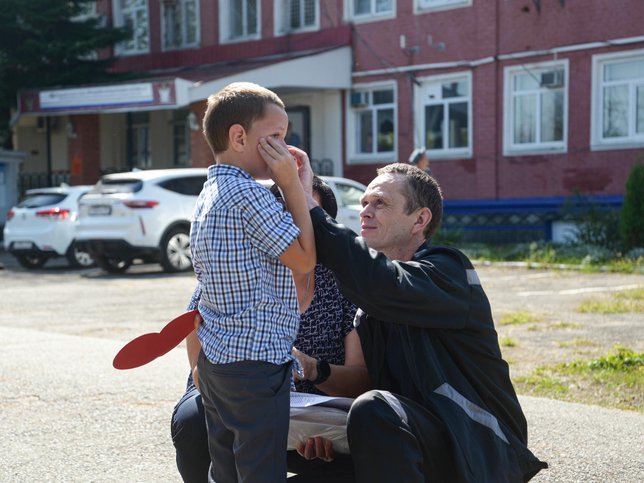 Maksim Beltikov wiping tears from his youngest son's face